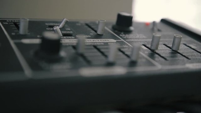 Analog vintage synthesizer, filters and volume controls, sliders and knobs, rack focus