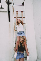 lifestyle and people concept: Fashion portrait of two stylish girls best friends wearing jeans skirts, outdoors on the roof. Happy summer time for fun.