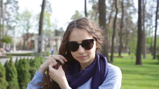 Beautiful young woman in sunglasses braids plait in summer park