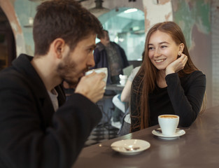 Young happy hipster couple in love having dating in a cafe. drink coffee,  talk and smile. Lifestyle. Relations between man and woman.
