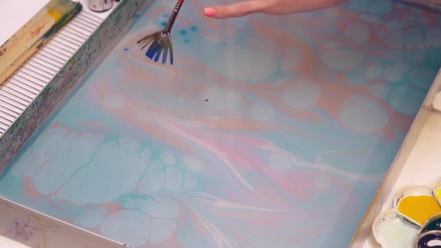 An artist drops paint into the water creating ebru picture