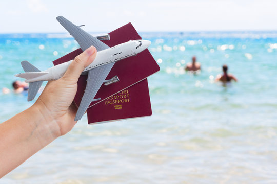 Plane travel concept, hand holding passports with plane over summer sea background