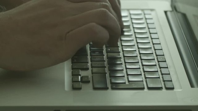 Close up of a man fingers typing on a laptop computer keyboard