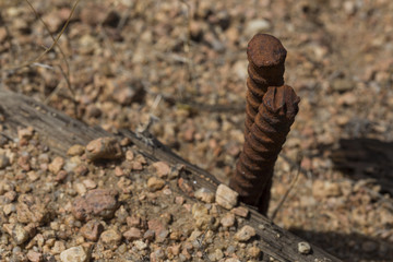Rusty metal screw spikes in stone ground