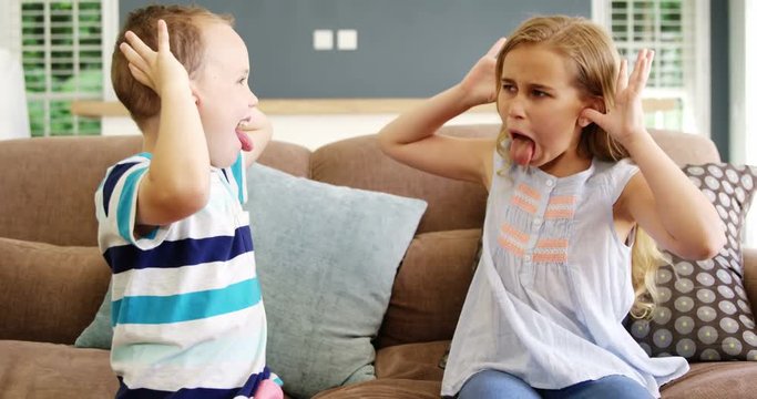 Boy and girl sitting on sofa teasing each other