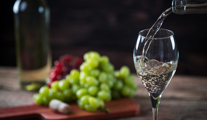 Pouring  glass of wine from a bottle of the wineglasses over rustic brown wooden background with copy space