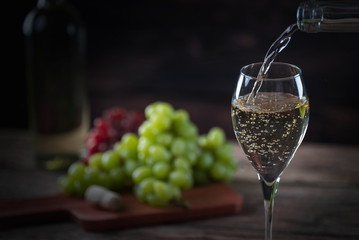 Pouring  glass of wine from a bottle of the wineglasses over rustic brown wooden background with copy space