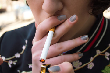 A woman smokes in the street. Close up