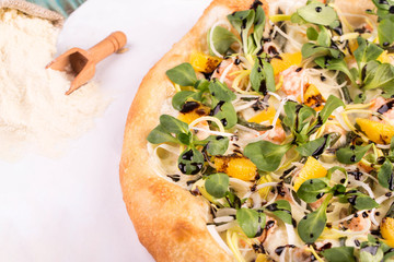 Piece of pizza with a salmon, cheese sauce, orange fillet, leek and haricot
