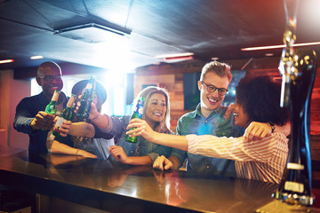 Obraz na płótnie Canvas Friends gesturing cheers with beer at tavern