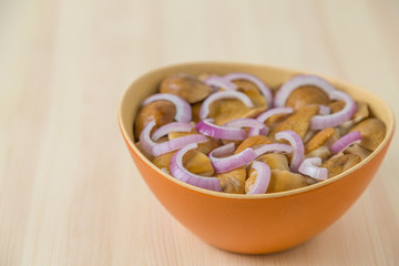 Marinated mushrooms with onion in a salad bowl