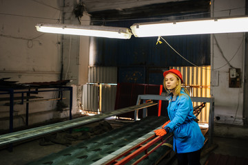woman in red safety helmet at metal tile roof manufacturing factory