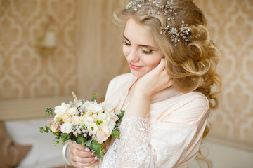 Obraz premium Pretty young girl. Blonde woman with luxurious long curly hair. Boudoir morning of the bride. Taking wedding bouquet in her hands