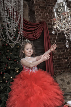 Little girl in red princess dress and chandelier with crystal
