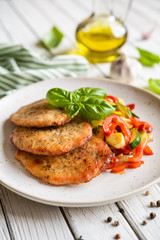 Fried pork fillets served with steamed zucchini, red bell pepper and garlic