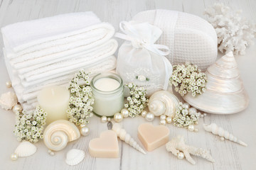 Fototapeta na wymiar Bridal Spa Beauty Treatment Products and Accessories. With flowers, shells and pearls on distressed white wood background.