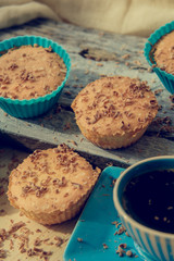 Chocolate muffin with soft cream and fresh blueberry powdered with sugar, cup of coffee, rustic background