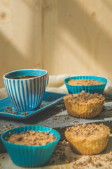 Chocolate muffin with soft cream and fresh blueberry powdered with sugar, cup of coffee, rustic background