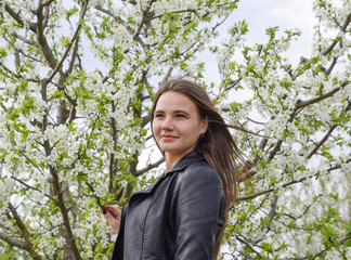 Beautiful fairy young girl in a flowering plum garden. Portrait of a girl on a white flowers background