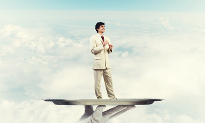 Obraz premium Businessman on metal tray playing fife against blue sky background