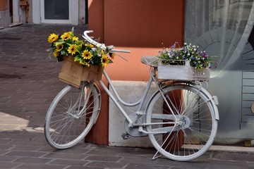 Bicicletta bianca con fiori nel cestino