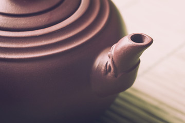 Close-up ceramic brown  chinese  teapot on green bamboo wooden background. Retro filter.