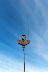 Obraz premium Hook of a construction crane on a wire blue background with a blue sky