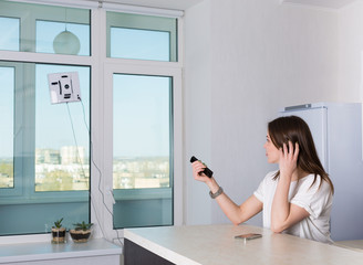 Woman cleaning windows with robotic cleaner