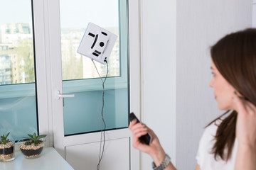 Woman cleaning windows with robotic cleaner