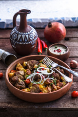 Big ceramic plate with roasted meat and potatoes with onion and wine. Traditional Georgian dish ojaxuri.