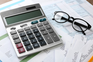 Calculator with documents and glasses on table. Tax concept