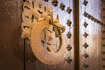ancient brown wooden door with metallic ornaments and a handle shaped as a dragon head
