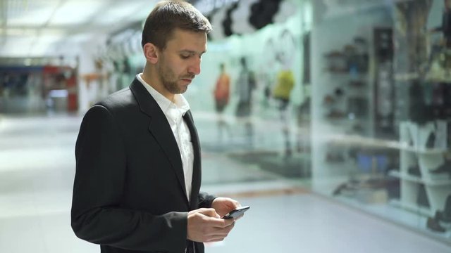 Serious businessman texting on smart phone and ooking aside in trade centre 4K