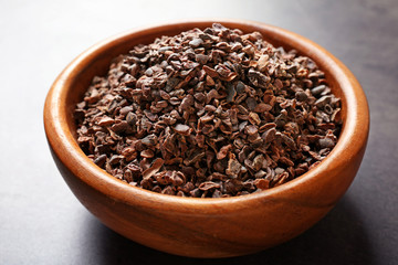Bowl with aromatic cocoa nibs on gray table