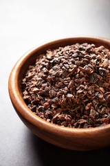 Bowl with aromatic cocoa nibs on gray table