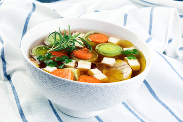Broth with carrots, onions various fresh vegetables in a pot - colorful fresh clear spring soup. Rural kitchen scenery vegetarian bouillon or stock