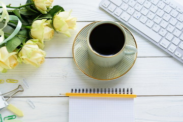 Holiday concept.Flat lay, top view office table feminine desk. workspace with laptop, notebook, cup of cofee and bouquet cream roses.