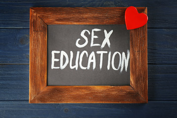 Small blackboard with text SEX EDUCATION on wooden background