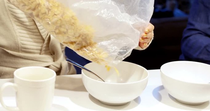 Mid-section of woman pouring cereals in bowl