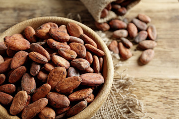 Bowl with aromatic cocoa beans on wooden table