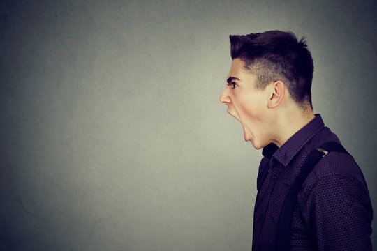 Side profile portrait of young angry man screaming