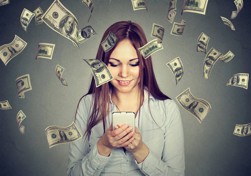 Woman using looking at her smart phone under money rain