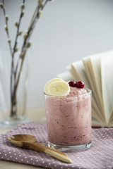 Curd breakfast with banana and cranberries in a transparent jar on a pink napkin