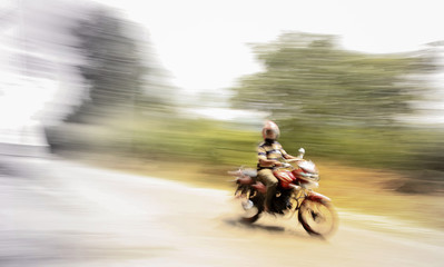 Fast motorbike drive, driver sitting on motorbike, blurred photo to show motion