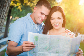 Happy Mixed Race Couple Looking Over A Map Outside Together.