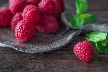 Ripe raspberries and mint on a wooden background. Organic food
