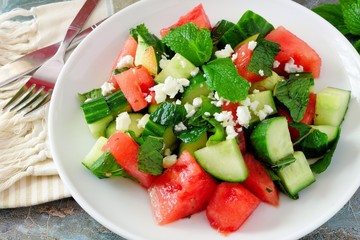 Summer salad with watermelon, mint, cucumber and feta cheese close up in a white plate
