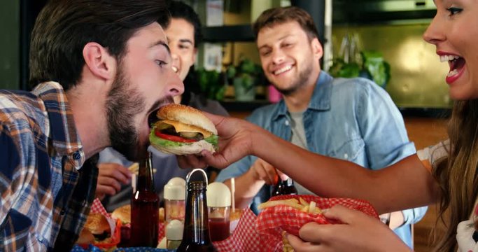 Woman feeding burger to man 