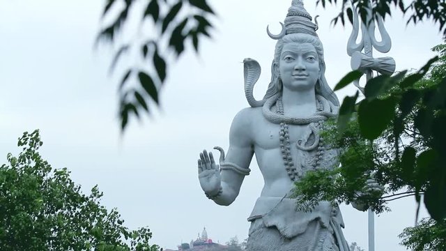 A large statue of the Hindu god Shiva looking over the ghats of Haridwar