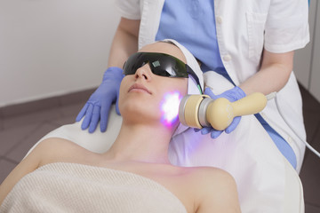 Face skin care. Woman getting facial laser treatment